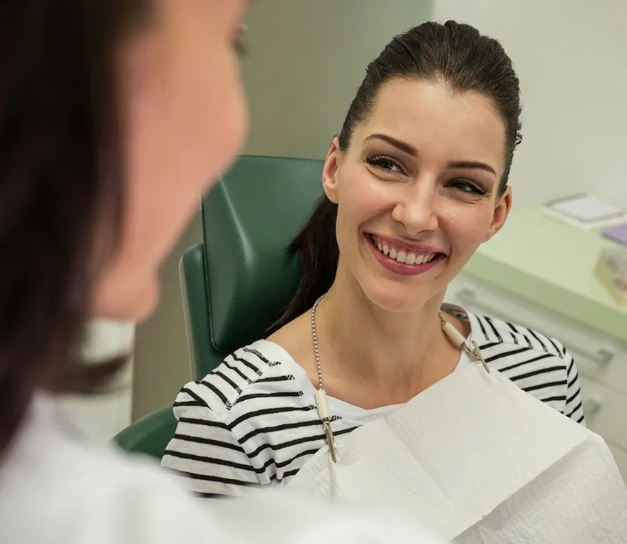 A smiling patient chatting with her dentist during a consultation