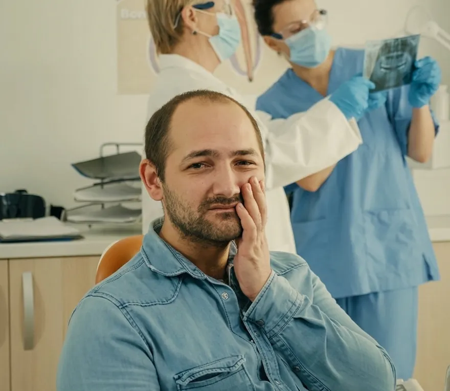 A dentist gently assessing a patient's jaw joint and muscles during a TMJ examination